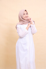 woman asian hijab wearing beautiful Muslim dress cheerful poses hands holding front of shoulders isolated on cream background. beauty, model, studio and fashion concept