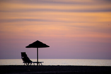 sunset at the beach, silhouette of umbrellas and people on the beach of Piscinas Ingurtosu. Medio...