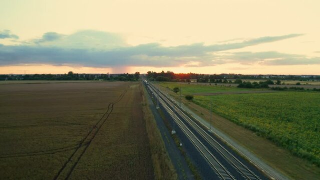 Passenger train weaves through field connecting Czech cities. Blue train smoothly travels along rails in picturesque Czech countryside at twilight