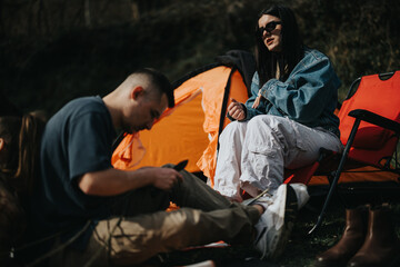 Group of friends relaxing and bonding on a camping adventure in the wilderness, representing...