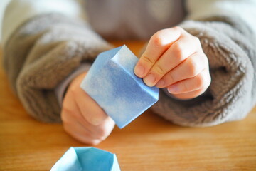 小学生の子供が折り紙を折っている手元。小学4年生、10歳。
