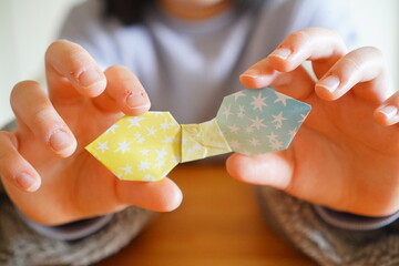 小学生の子供が折り紙でリボンを折った。小学4年生、10歳。