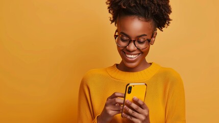 A radiant woman smiles joyfully at her phone, set against a vibrant yellow backdrop, ideal for tech and lifestyle concepts