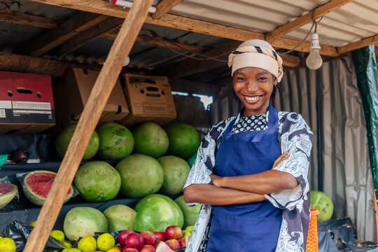 Attractive African Saleswoman at Fruit Stand with Folded Arms