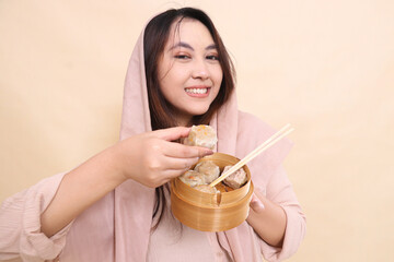 happy asian girl in hijab holding dimsum and wooden bowl fore containing chopsticks and tasty and...