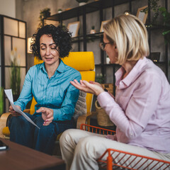 two women work on project at home hold document have consultation