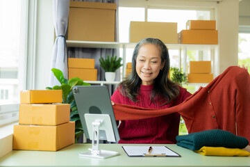 Happy mature businesswoman, small business owner in warehouse office There are parcel boxes piled...