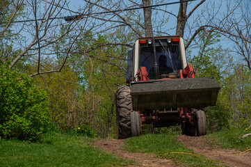 Fototapeta premium A man driving a red tractor full of gravel in the bucket during spring on a sunny day