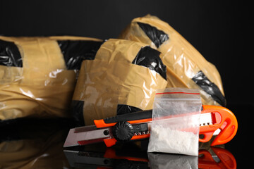 Smuggling, drug trafficking. Packages with narcotics and utility knife on black mirror surface,...