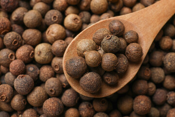 Aromatic allspice pepper grains and wooden spoon, top view