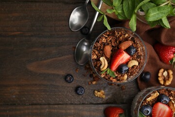 Obraz na płótnie Canvas Tasty granola, berries, nuts and mint on wooden table, flat lay. Space for text