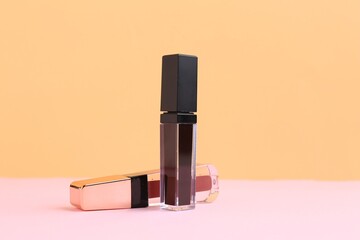 Two lip glosses on pink and orange background