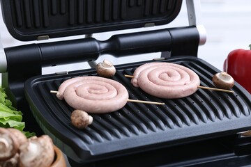 Homemade sausages and mushrooms on electric grill, closeup