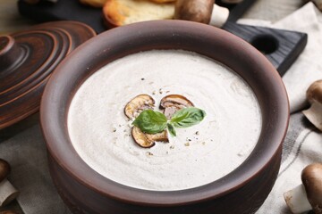Fresh homemade mushroom soup in ceramic pot on table, closeup