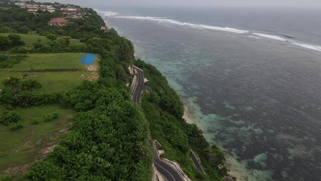 Aerial view, cliffside asphalt road and sea located on Tanah Barak beach, Bali island, Indonesia.