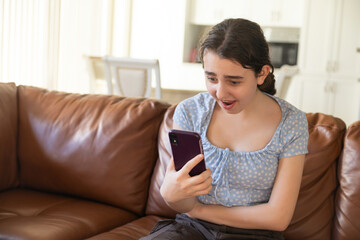 Surprised Teen Viewing Smartphone Screen. A teenage girl exhibits a shocked expression while...