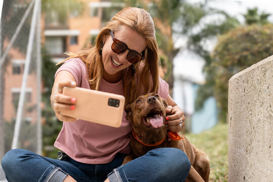 A woman takes a selfie with her dog outdoors.