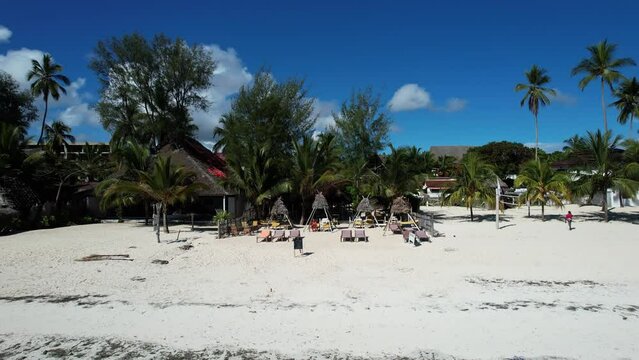 Aerial view of tropical Kiwengwa beach with palm trees, boats, and hotel under sunny sky Zanzibar Drone Pilo Tanzania Africa