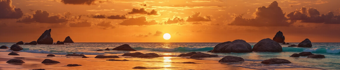 A beautiful beach scene with a sunset over the ocean. The beach is covered in rocks, and the water is calm with a slight wave rolling in.