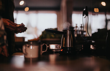 A close-knit scene of friends in a home kitchen with a kettle and cups, evoking warmth and...