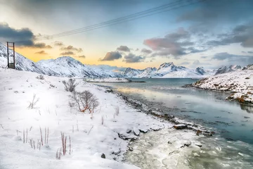 Photo sur Plexiglas Reinefjorden Stunning morning view of Torsfjorden fjord with cracked ice and snowy mountain peaks at background.