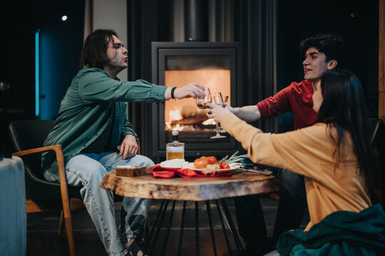 Cheerful friends toasting glasses in a warm, inviting home setting with a fireplace in the background