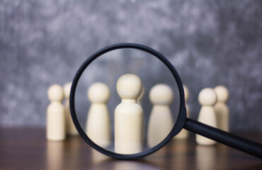 Magnifying glass looking at wooden doll The concept of recruiting people to work and become...
