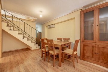 Cherry wood dining table with matching chair in the corner of the living room of a two-story house...