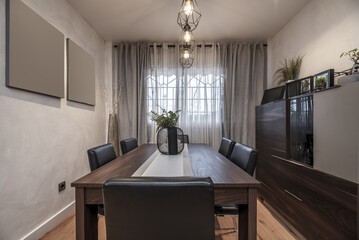 Living room with dark wood dining table matching bookcase and black upholstered chairs