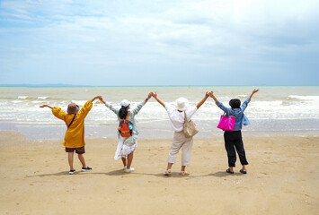 senior friends enjoy a sunny day at the beach. The group's laughter and active engagement create a...