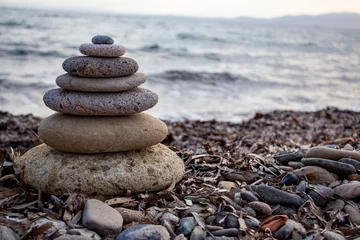 Tuinposter Stack of zen stones on the beach. Zen and harmony concept. Pyramid of pebbles on the beach at sunset. Stack of zen stones on the seashore. Zen concept © Caneritir