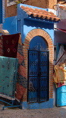 Colorful rugs and textiles hanging around an arched doorway in Chefchaouen, Morocco