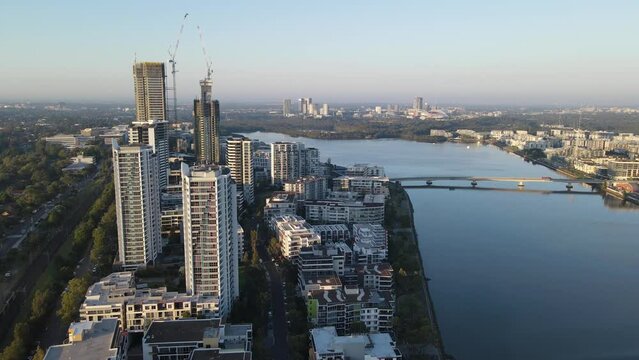 Aerial drone pullback reverse view of Rhodes, an Inner West suburb of Sydney, and Homebush Bay, NSW Australia on a sunny morning in March 2024 
