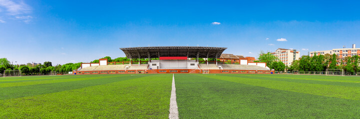The unmanned outdoor football stadium is located on the university campus, with clear skies