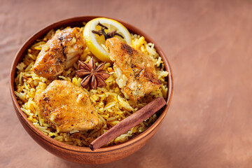 Chicken Biryani with Fried Chicken, Spices and Lemon on Brown Background, Top View, Copy Space