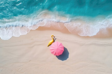 Aerial view of pink umbrella and yellow flamingo on sandy beach near ocean with waves