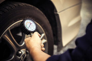 Hand car mechanic holding car tire pressure check equipment tool to checking low tire pressure...