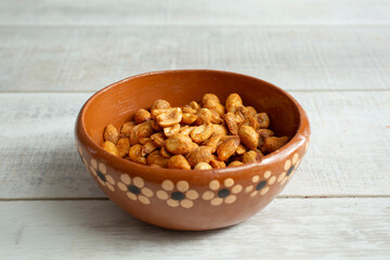 A view of roasted peanuts in a clay bowl.