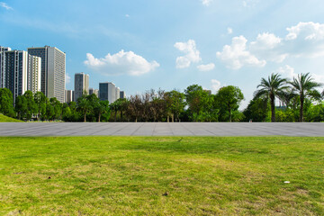 Outside the flat and vast square is a vast urban park, under a clear sky in summer