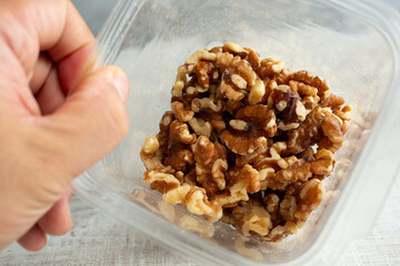 A view looking into a plastic container of walnut pieces.