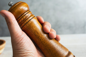 A view of a hand holding a wood pepper grinder tool.