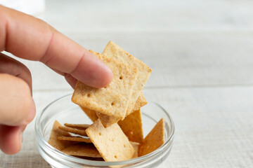  A view of fingers holding some almond flour crackers.