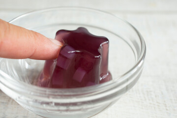 A view of a hand poking at a star shaped gelatin snack.