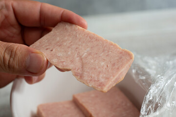 A view of a hand holding a slice of spiced ham.