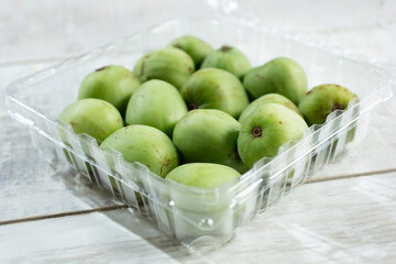 A closeup view of a plastic container full of kiwi berries.