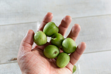 A top down view of several kiwi berries in the palm of the hand.