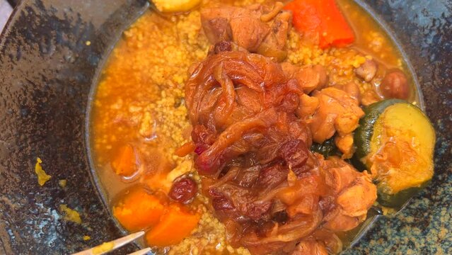 Eating delicious tender chicken with couscous and vegetables in a restaurant, traditional Moroccan dish, slow cooked meat, 4K shot