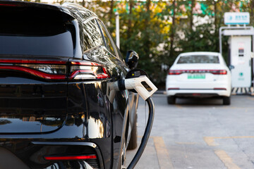 A black new energy electric vehicle is being charged at a charging station using a charging station