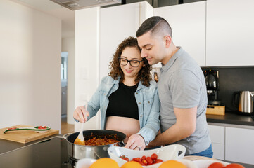 Tender pregnant couple cooking together at home