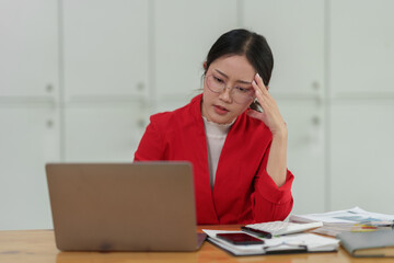 Young independent businesswoman with glasses is tired, stressed, has a headache while sitting in front of a laptop for a long time and working in finance. Online. Office Syndrome concept.